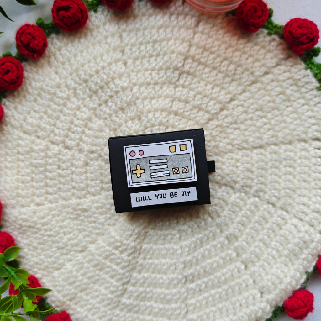 Handcrafted 'Will you be my Player 2' matchbox opened to reveal a tiny miniature game controller and a romantic message.